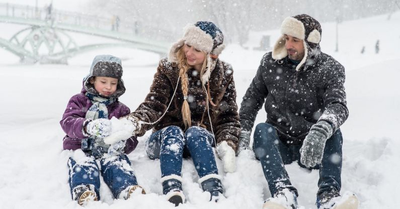 Winter Family Fun - Woman, Man and Girl Sitting on Snow
